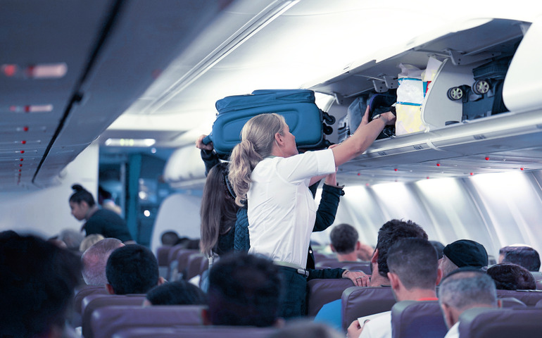 Person putting luggage in in overhead bin 
Image Credit: lunopark/Shutterstock