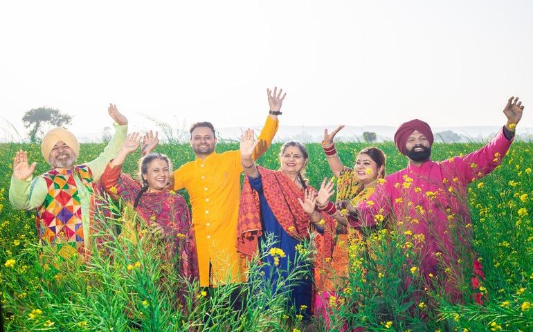 Punjabi Sikh family doing Bhangra in agriculture field celebrating Baisakhi
