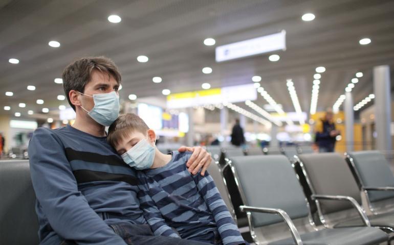 Young boy and his father wearing masks at the airport