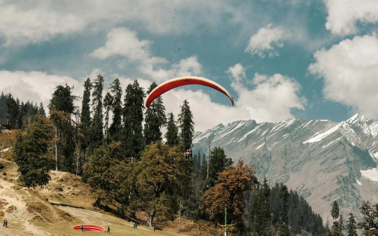 People Paragliding in Mountain Valley
