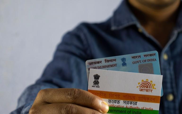 A man holding PAN and Aadhaar cards 
