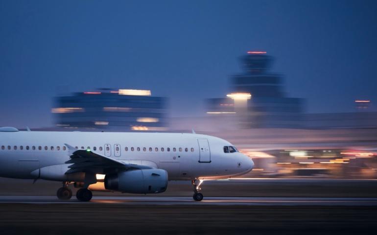 Airplane during take off on airport runway at night against air traffic control tower