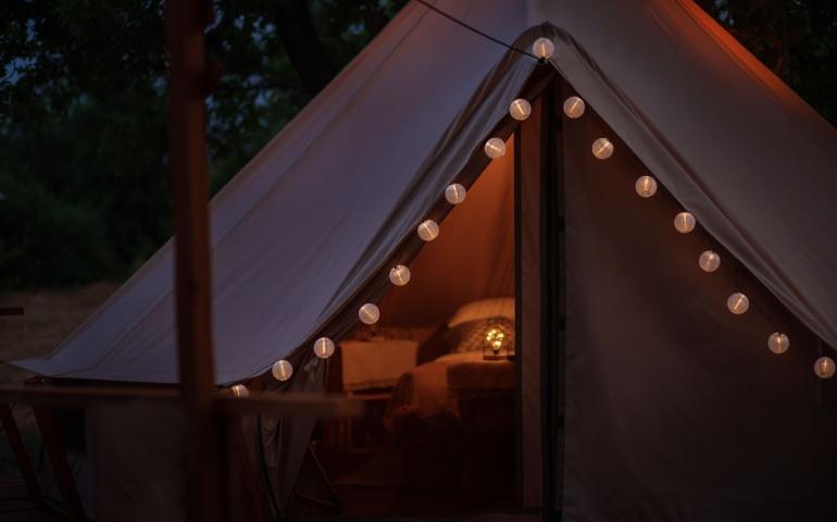 Lanterns glow on a tent in a campsite