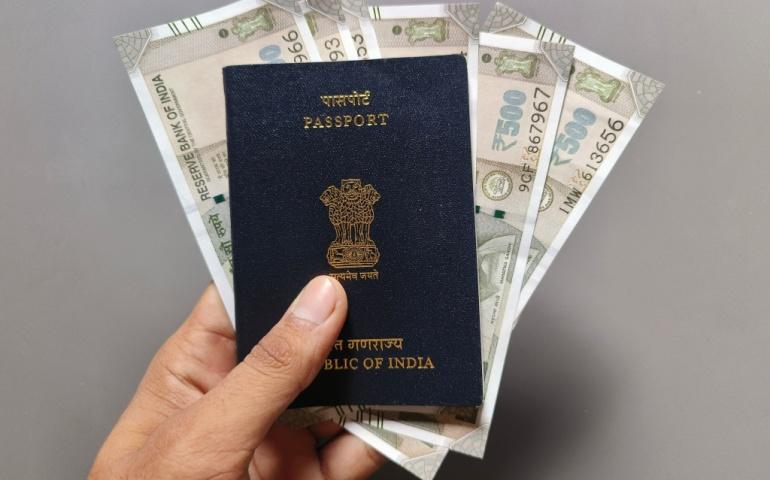 Man hand holding Indian passport and Indian currency