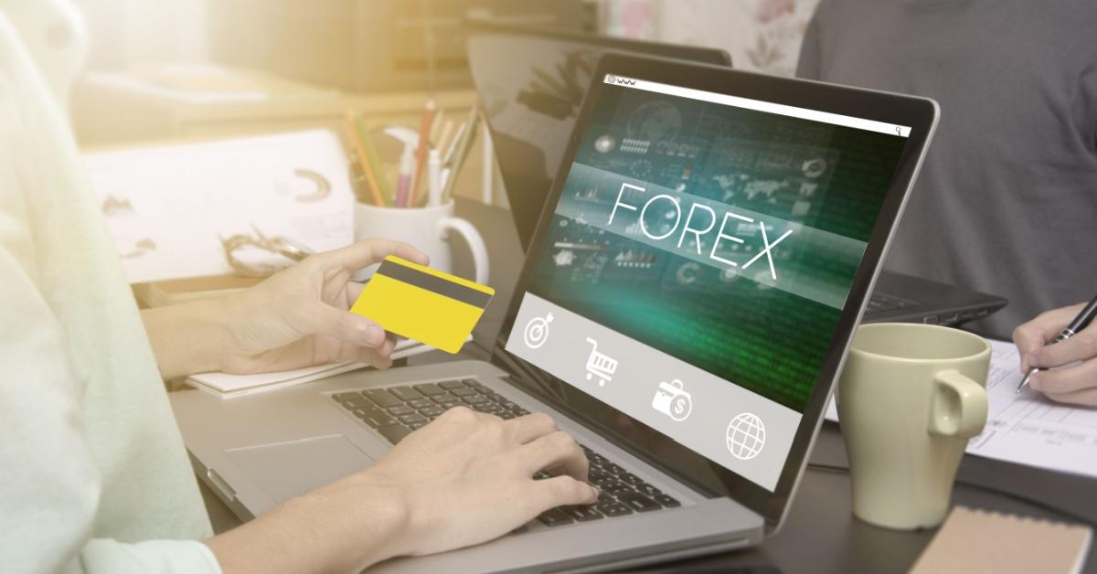 hand typing on computer keyboard with credit card and Forex homepage