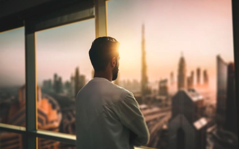 A young man looking out through a hotel window in Dubai