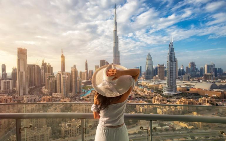 A tourist standing on a balcony overlooking the Dubai skyline