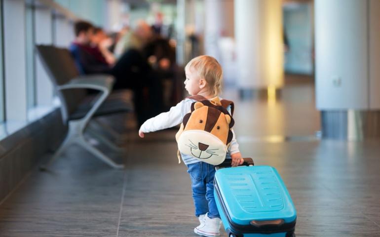A child dragging a suitcase at the airport
