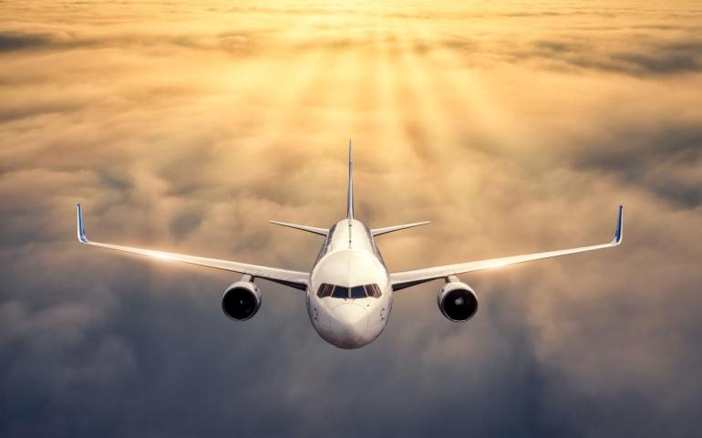 An airplane is Flying above the Clouds at Sunset 