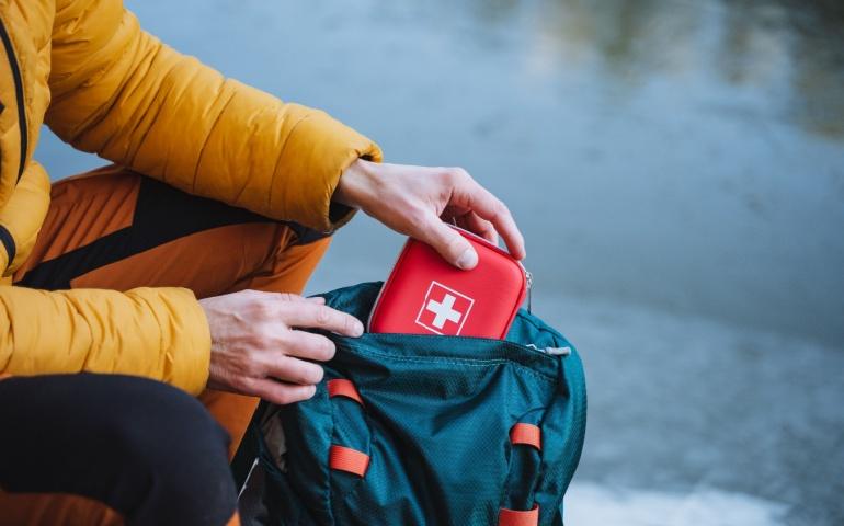 A guy puts a first aid kit in a backpack