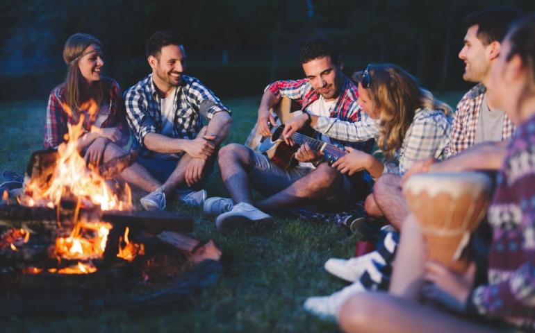 People playing music and enjoying bonfire in nature
