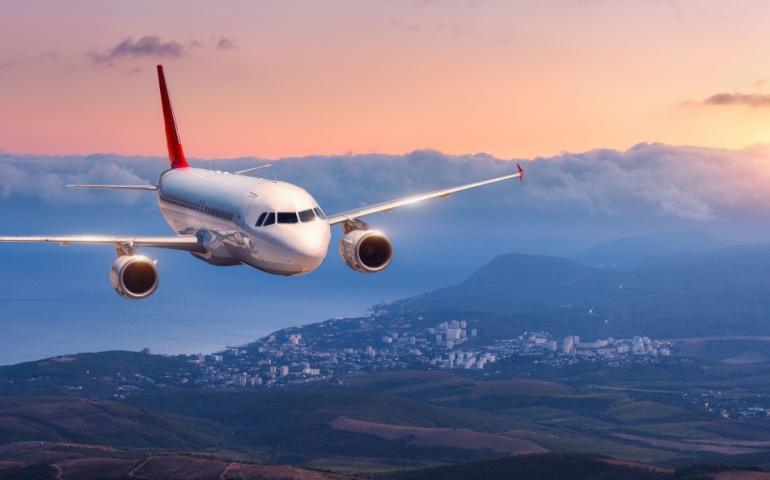 Plane Flying with Clouds over Mountains at High Altitude