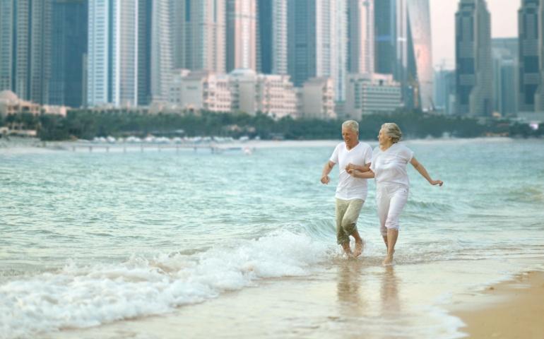 A couple running on the beach with skyscrapers in the background
Image Credit: Ruslan Huzau/Shutterstock