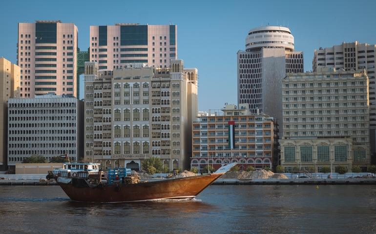 View of traditional wooden dhow boat sails in front of Carlton Dubai Creek Hotel