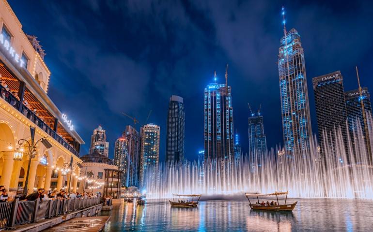 People enjoying boat ride on Burj Khalifa Lake while watching the Dubai Fountain show at night