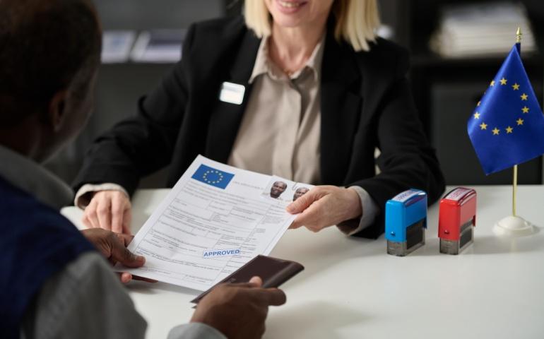 Officer handing approved visa application form to tourist