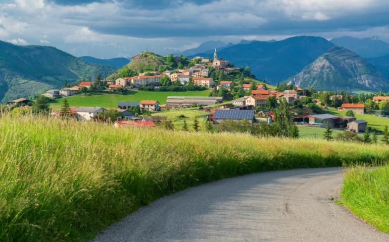Sunny alpine valley with old town on the hill top. Southern France