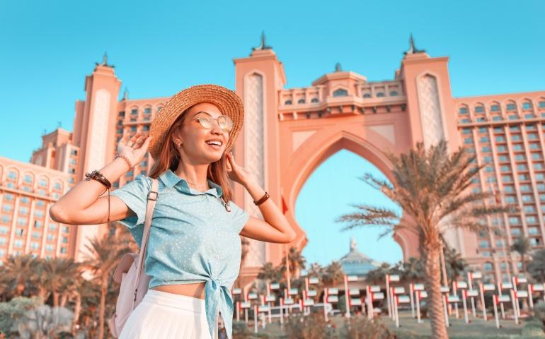 Happy tourist in front of luxury Atlantis hotel building on a Jumeirah Palm Island
