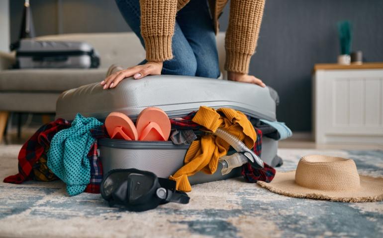 Woman Trying to Close Overload Travel Suitcase