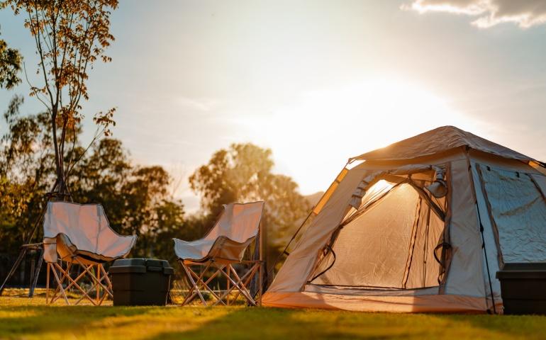 Camp near the lake with sunrise at mountains in the background