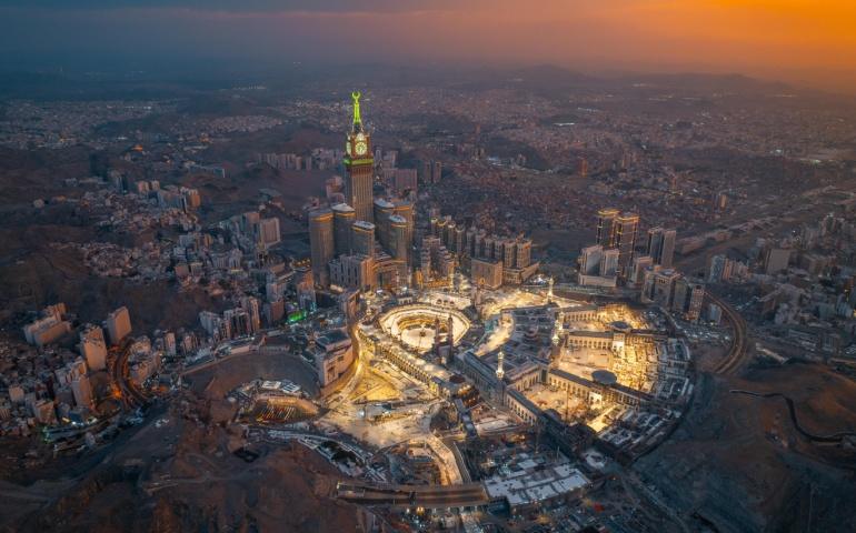 Aerial view at night of the illuminated Grand Mosque and Abraj Al-Bait Clock Tower in Mecca
