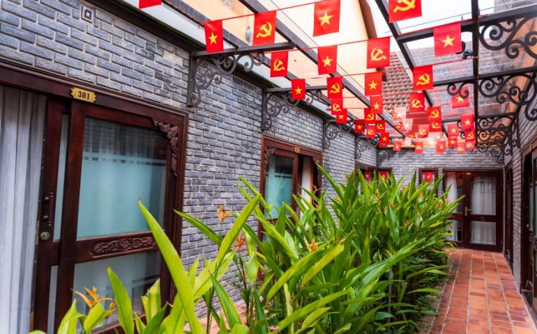 A vibrant guesthouse walkway, decorated with strings of Vietnamese communist flags 