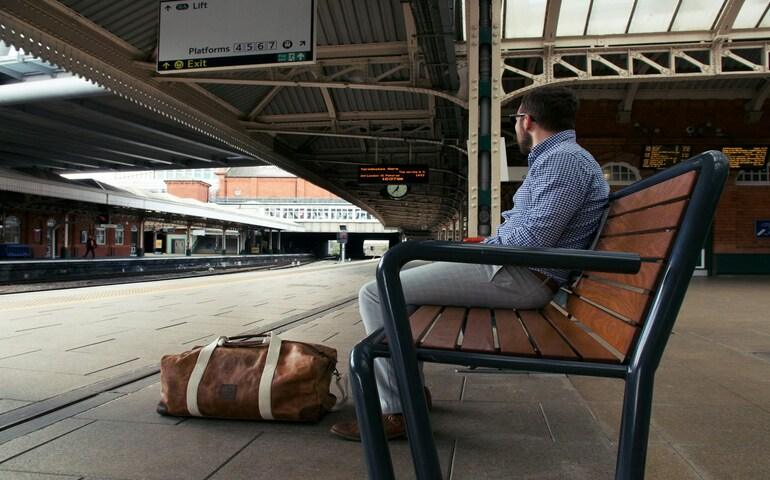 A man sitting at the station waiting for his train