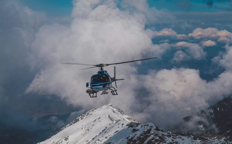 Helicopter flying over snow-covered mountains