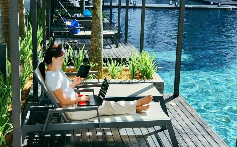 A woman working on her laptop beside the pool