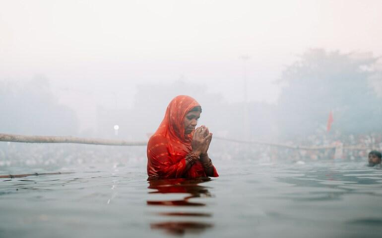 A woman dipping in the river for Chhath Puja