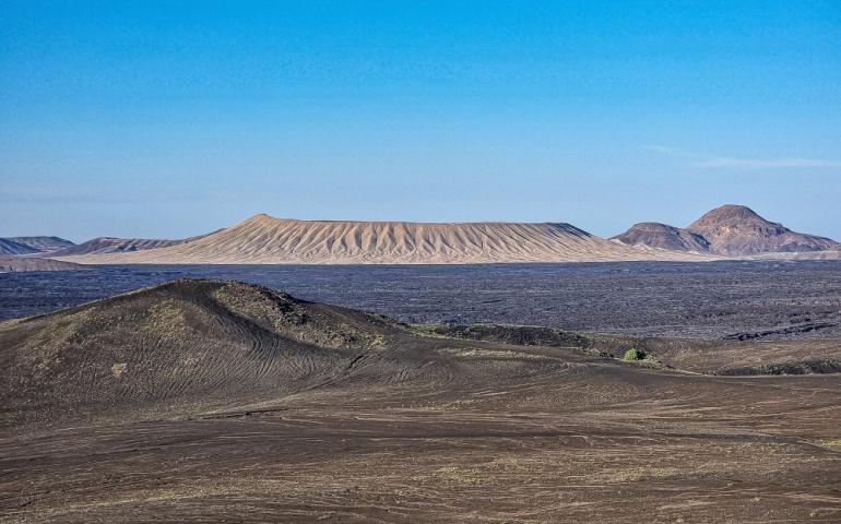 A volcanic landscape with multiple mountains and lava fields. Harrat Khaybar, KSA. 
