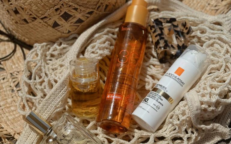 Beach Bag with Sunscreen and Perfume Bottles near Straw Hat