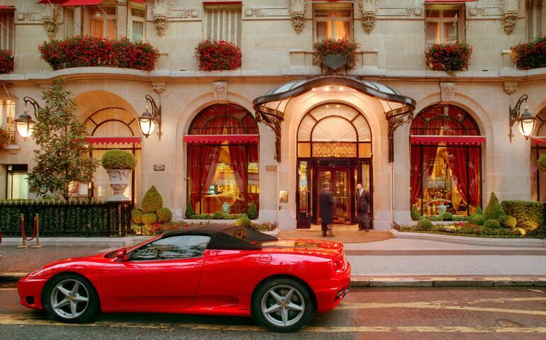 A Red Ferrari Car Parked on the Street in Front of the Hotel
