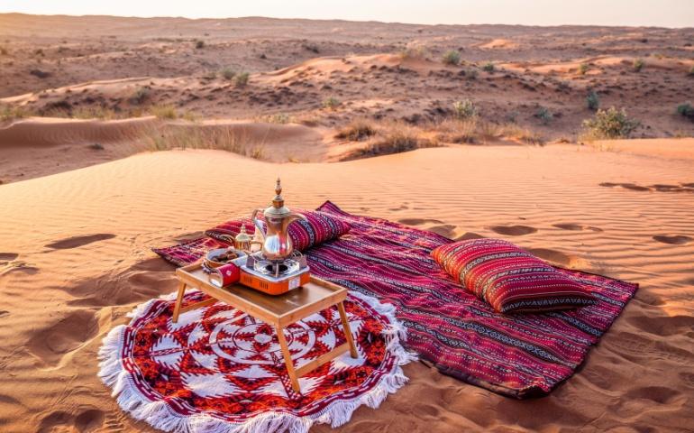Authentic desert majlis with Arabic carpet, dallah coffee pot, and cushions in the Arabian desert