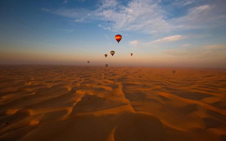 A Hot Air Balloons Flying Over Sand