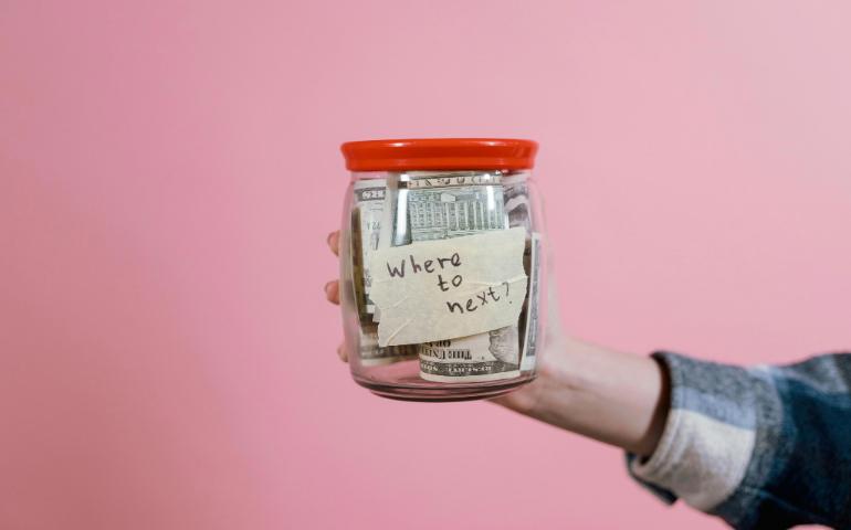 A Person Holding a Glass Jar with Money