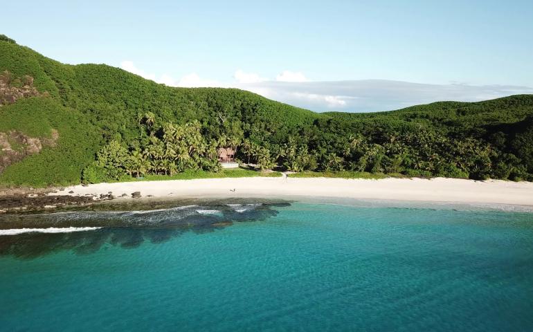 a beach with trees and hills in the background
