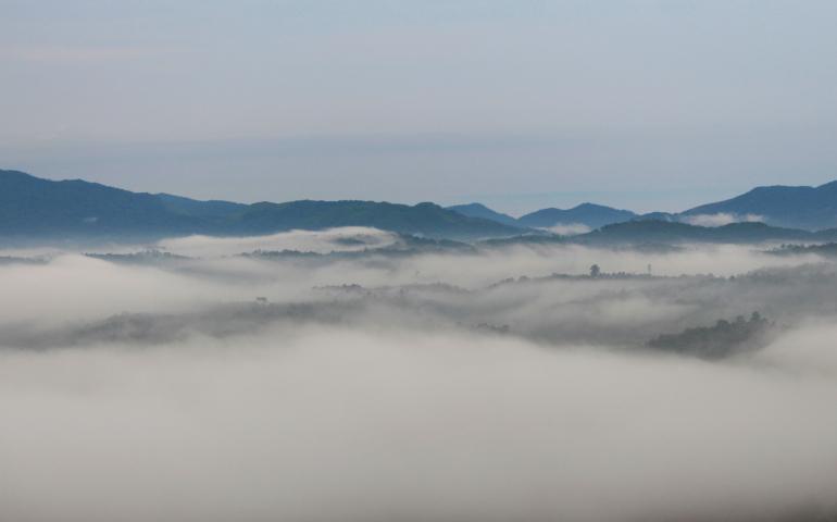 a foggy valley with mountains in the distance