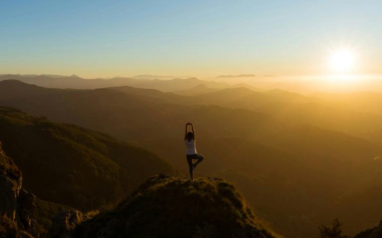 A woman doing yoga on mountain
