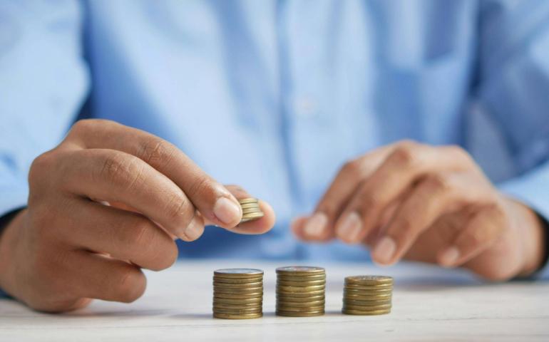 Person Stacking Coins on the Table