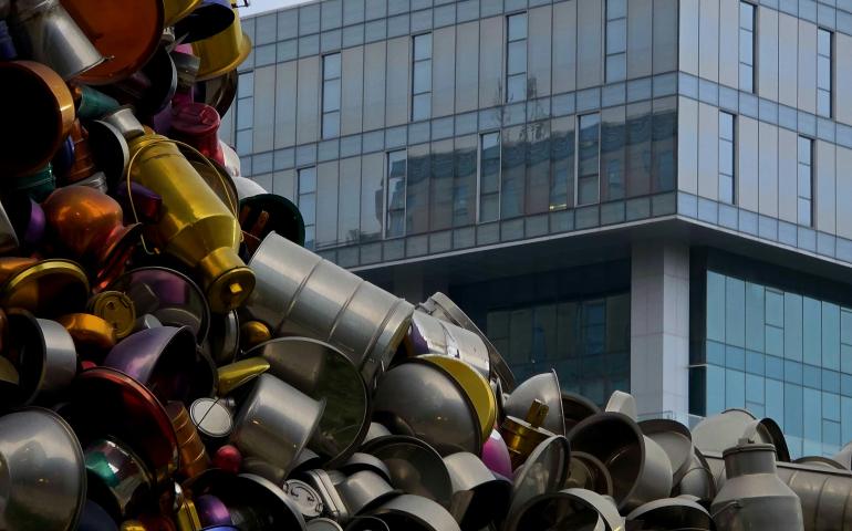 Pile of metal pots and pans with modern building
