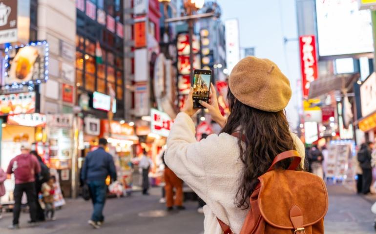 Traveller taking pictures and navigating Osaka, Japan with a smart phone