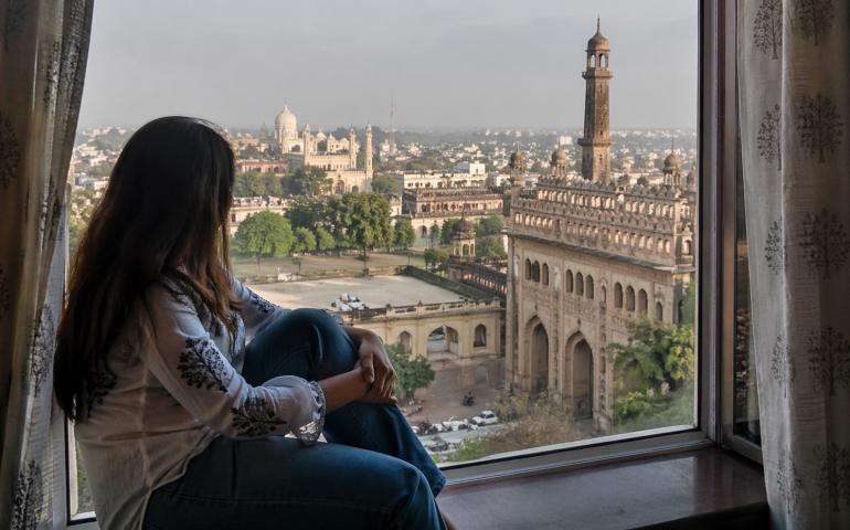 Traveler sitting by a window overlooking Lucknow city
