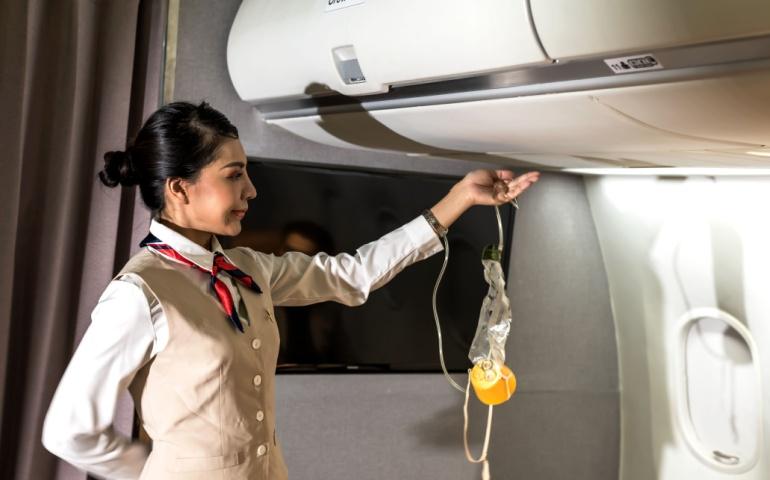 The flight attendant demonstrates on how to use oxygen equipment