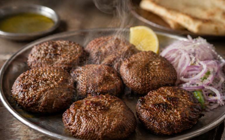 A tray of steaming Tunday Kababi served on a simple metal plate
