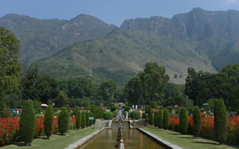 Beautiful Mughal Garden in Srinagar With Red Flowers and Mountains Under a Clear Blue Sky