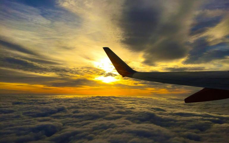 A Breathtaking View of an Airplane Wing Above Clouds During a Vibrant Sunset

