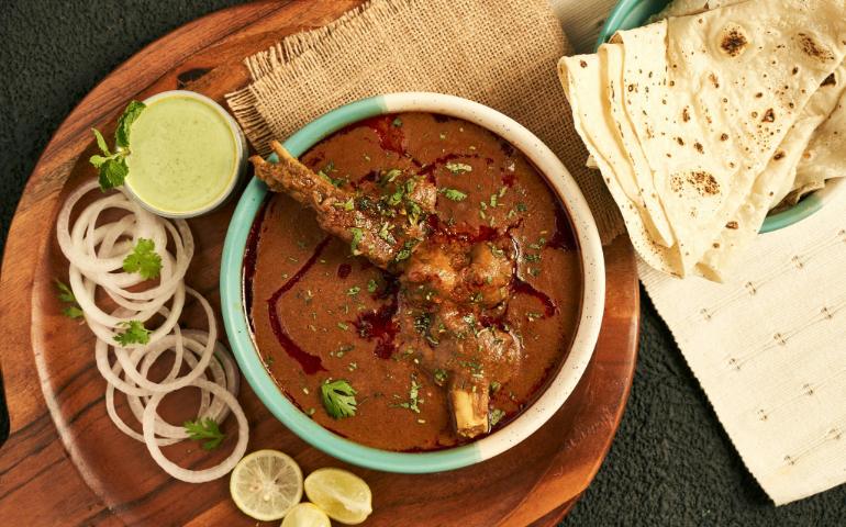 Indian Curry Served with Flatbread and Garnished with Onions and Herbs
