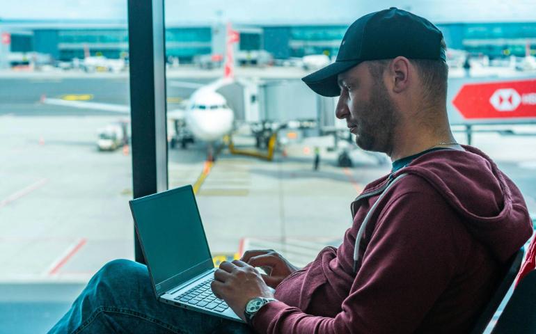 A Man Working on his Laptop in an Airport Terminal.