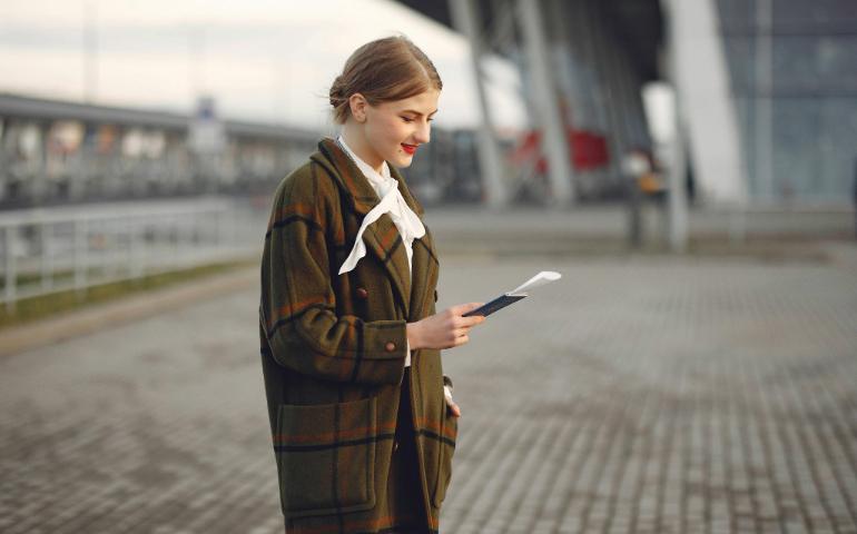 Smiling Young Woman at Station Holding Passport, Ready for Travel